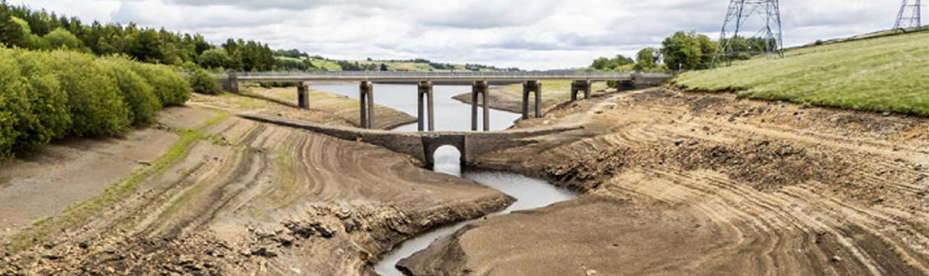 Landscape image of low river flowing under a bridge