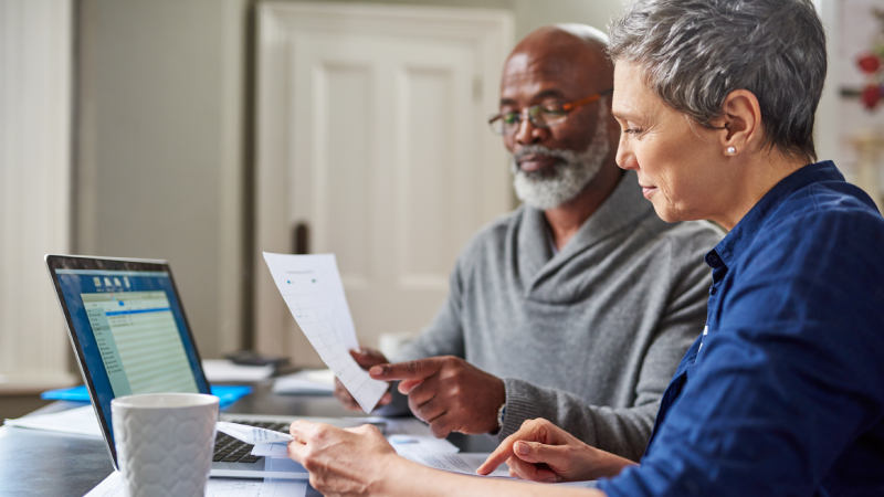 Two people looking at piece of paper and a laptop