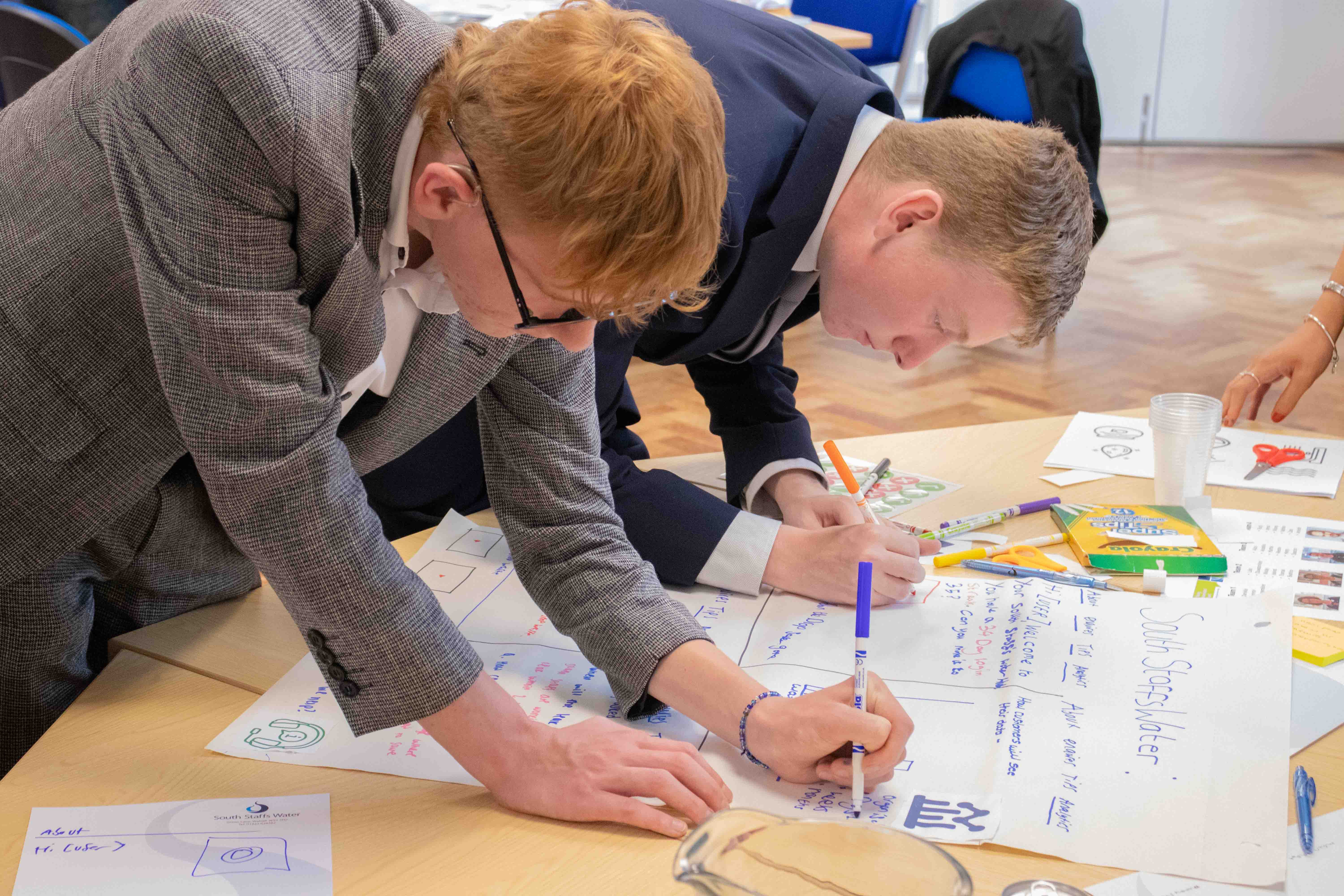 Two students writing on a A3 piece of paper