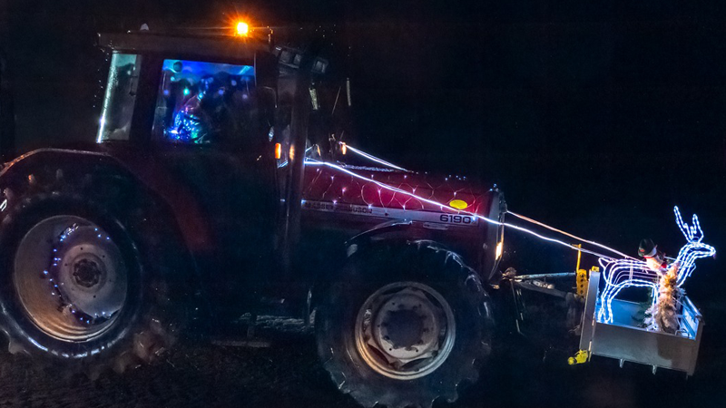 Tractor decorated with Christmas lights and lit up reindeer