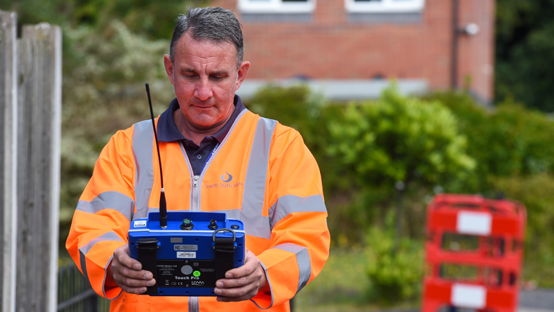 A leakage technician looking at his device near safety barriers